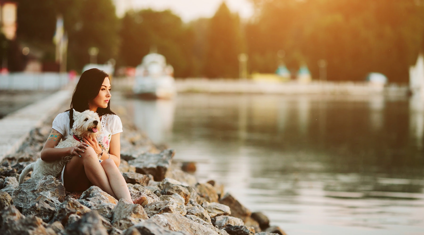 Woman holding dog and sitting by lake